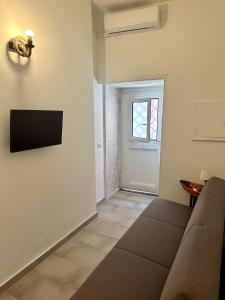 a living room with a couch and a television on the wall at Ercolano Civitas in Ercolano
