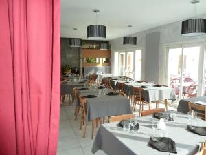 uma sala de jantar com mesas e cadeiras com cortinas cor-de-rosa em Le Pidanoux em Saint-Julien-du-Verdon
