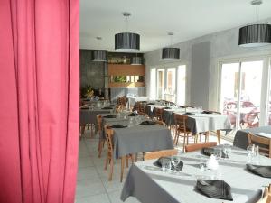 a dining room with tables and chairs with pink curtains at Le Pidanoux in Saint-Julien-du-Verdon