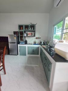a kitchen with green cabinets and a stainless steel refrigerator at Huahin Friends Pool Villa 1 in Hua Hin