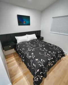 a bedroom with a bed with a black and white comforter at LuxQuarters Huckleberry Suite in Kitimat