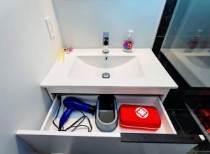 a white bathroom sink with a red box underneath it at LuxQuarters Blueberry Studio in Kitimat