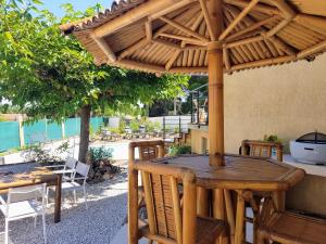 a wooden table and chairs under a wooden umbrella at Villa Palmera - Classée 3 étoiles - Grand confort, calme, et magnifique vue dégagée in Canet