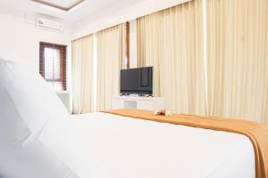 a bedroom with a white bed and a television at Gita Bali House in Nusa Dua