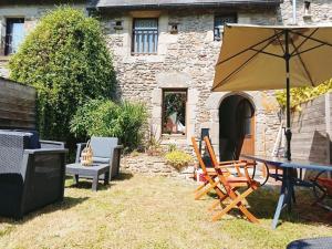 a patio with a table and chairs and an umbrella at 17th century house with swimming pool in Pleurtuit