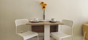 a table with two chairs and a vase with flowers on it at Caparica Studio - Sclusive Stay in Costa da Caparica