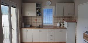 a kitchen with white cabinets and a sink and a refrigerator at EA1 Jablaničko jezero in Konjic