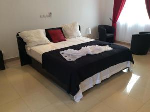 a bed with a black and white sheets and pillows at Guest Wharf in Pointe-Noire