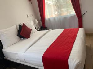 a large bed with red and white sheets and pillows at Guest Wharf in Pointe-Noire +2 photos