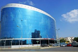 فندق جراند ميرال في الخبر: مبنى ازرق فيه سيارات تقف في موقف للسيارات