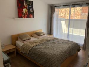 a bedroom with a bed with two pillows and a window at Duplex Jaden - 3 pièces climatisé 80m2 in Villeveyrac