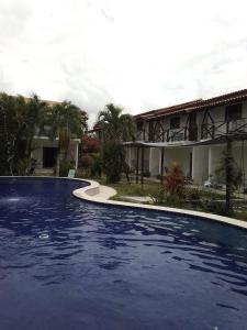 a large blue swimming pool in front of a house at Falésias de Carapibus in Jacumã