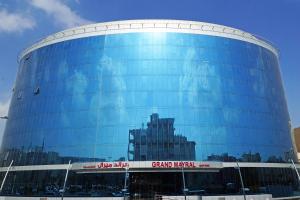 un gran edificio de cristal con un cartel. en Grand Mayral Hotel, en Al Khobar