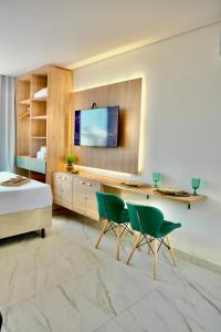 a bedroom with a bed and a desk and two green chairs at Feel Home - Flat Sofisticado Próximo a Praia in Cabedelo +20 photos