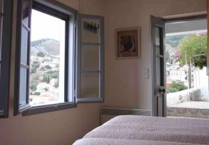 Cheerful 2-bedroom villa with gorgeous terraces في هيدرا: غرفة نوم بها سرير ونافذة مفتوحة