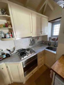 Cheerful 2-bedroom villa with gorgeous terraces في هيدرا: مطبخ بخزائن بيضاء وفرن موقد