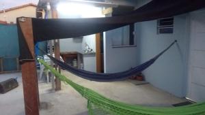 Un hamac est fixé sur le côté du bâtiment. dans l'établissement Casa familiar quarto, cozinha, banheiro e piscina a praia está a 700 metros, à Peruíbe