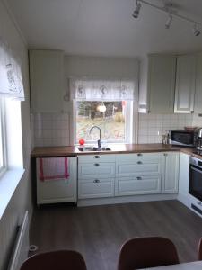 a kitchen with white cabinets and a sink and a window at Lyngen Brygge in Årøybukta