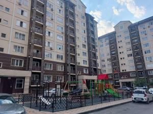 a parking lot with a playground in front of tall buildings at Уютная квартира в парковой зоне in Chong-Aryk