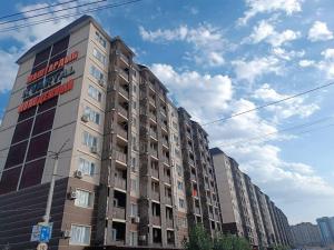 a tall building with a sign on the side of it at Уютная квартира в парковой зоне in Chong-Aryk +2 photos
