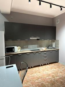 une cuisine avec des armoires noires et une table avec des chaises dans l'établissement Green Park Однокомнатная, à Aktau