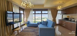 a living room with blue chairs and a large window at Serenity by Zen Residences at The Radiance Manila Bay in Manila