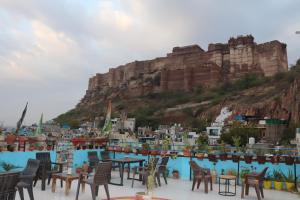 a group of chairs and tables in front of a mountain at Anne Guest House in Jodhpur