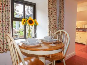 une table de salle à manger avec un vase de tournesols dessus dans l'établissement Rock Cottage, à Ashbourne