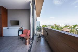 a balcony with red chairs and a television on a building at MARQUEE Playa Hotel in Playa del Carmen