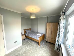 a bedroom with a bed and a dresser and a window at Cozy 3 Bedroom Home in Port Talbot