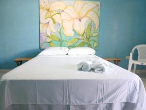 a bed with towels on it with a painting on the wall at Casa y Galeria de arte, Suchitoto in Suchitoto