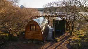 a small wooden house with a staircase in a field at Mountain view pod in Lochinver