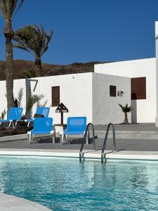 einen Pool mit blauen Stühlen neben einem Gebäude in der Unterkunft Villa Blanca Nudist Exclusive in Charco del Palo