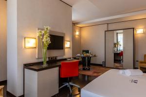 a hotel room with a bed and a desk with a vase of flowers at Hotel Valentino in Terni