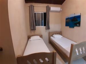 two beds in a small room with a window at SUITE 503 - Casa Astral - Praia da Pipa - Quarto de Solteiros in Pipa
