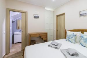 ein Schlafzimmer mit einem weißen Bett und ein Badezimmer in der Unterkunft SaltWater Peniche Apartments in Peniche