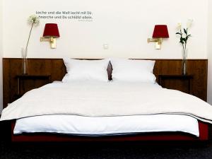 ein Bett mit weißer Bettwäsche, zwei Lampen und Blumen in der Unterkunft Hotel Restaurant Piärdestall Hövelhof in Hövelhof