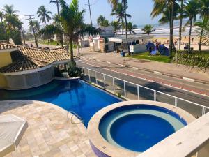 ein großes Schwimmbad neben einer Stadtstraße in der Unterkunft Jequitiba Hotel Frente ao Mar in Guarujá