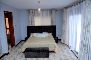 a bedroom with a large bed with white curtains at Daisy's Apartments in Bwebajja