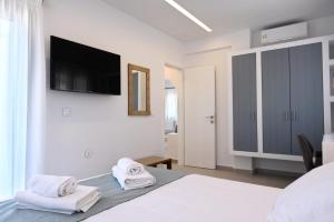 a white bedroom with towels on a bed with a tv on the wall at Pagada in Kithnos