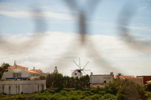 Blick auf eine Windmühle in einer Stadt mit einem Haus in der Unterkunft Ericeira Chill Hill Hostel & Private Rooms - Peach Garden in Ericeira