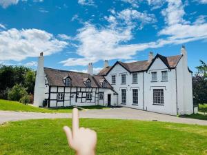 une personne pointant du doigt une grande maison blanche dans l'établissement Stylish Tudor Cottage & Hot Tub, à Coombe Hill