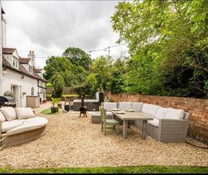 un patio avec des canapés et une table dans une cour dans l'établissement Stylish Tudor Cottage & Hot Tub, à Coombe Hill 31 autres photos