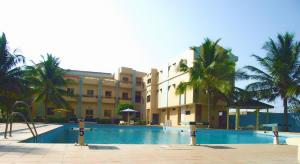 a hotel with a swimming pool in front of a building at Hotel Ghis Palace in Baguida