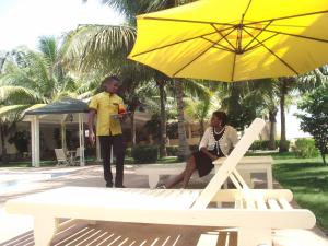 twee mensen op een bank onder een gele paraplu bij Hotel Ghis Palace in Baguida