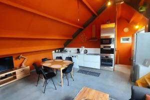 a kitchen with orange walls and a table and chairs at L'étape Saint-Joseph in Brunehaut +12 photos
