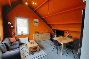 a living room with orange walls and a table at L'étape Saint-Joseph in Brunehaut