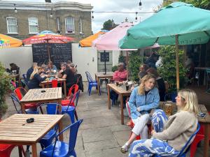 a group of people sitting at tables at an outdoor restaurant at The Brookmill in London