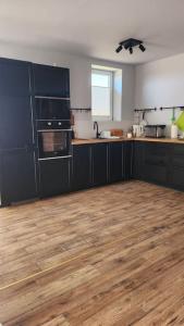 a kitchen with black cabinets and a wooden floor at Wspaniały cały 5 sypialniowy dom in Leleszki