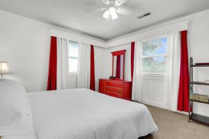 a bedroom with a white bed and red curtains at Charming Downtown Charleston, Near Hampton Park in Charleston